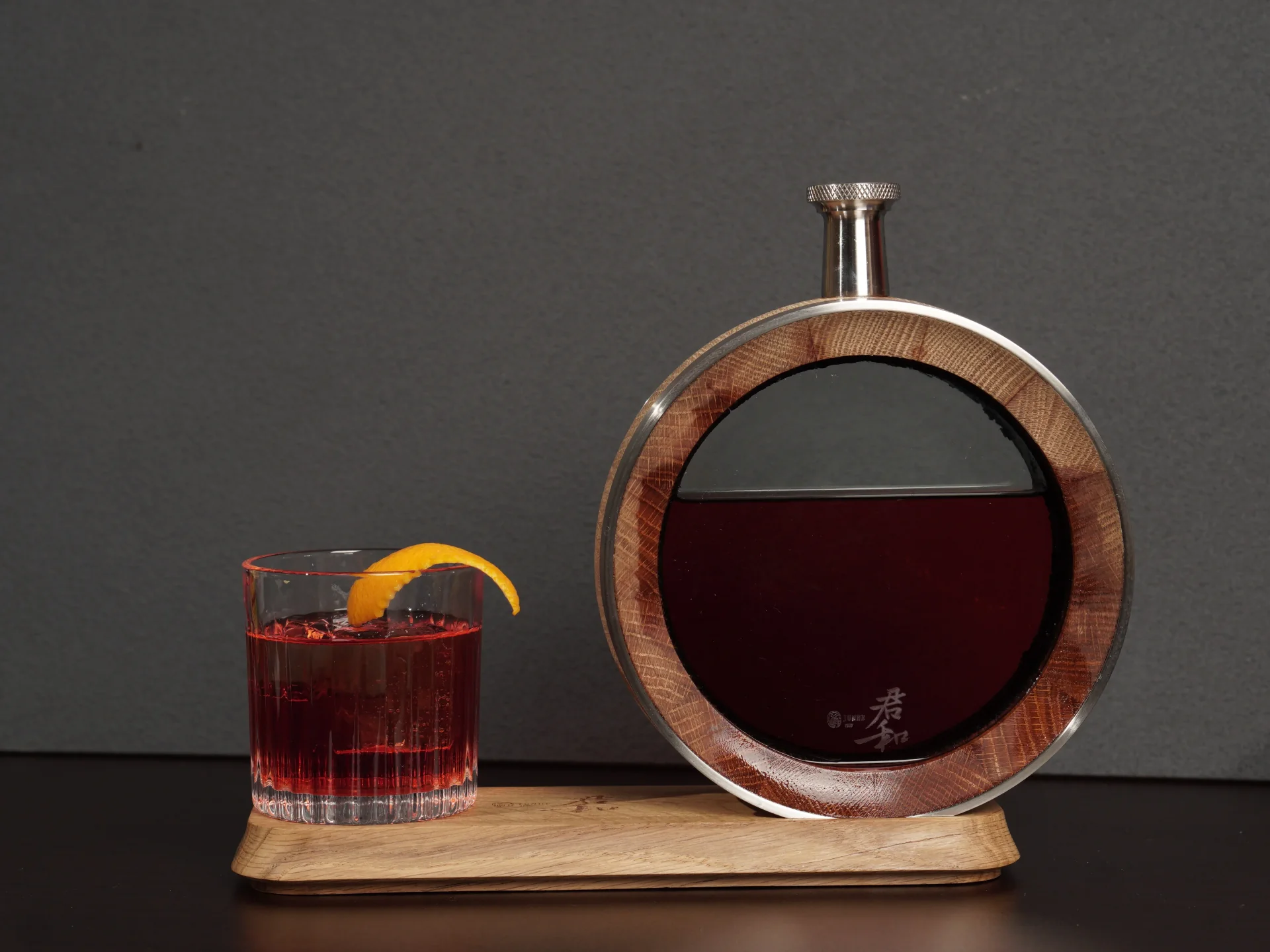 Junhe's 500ml visible oak decanter beside a cocktail glass on its wooden display base.